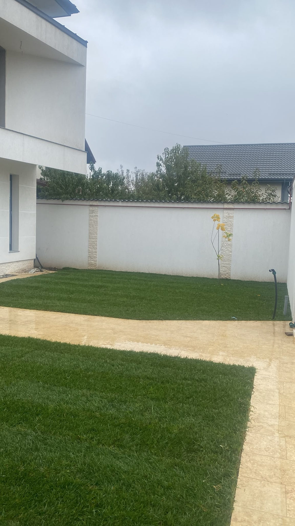 Curte cu gazon rulou proaspăt montat lângă alee din dale, casă nouă